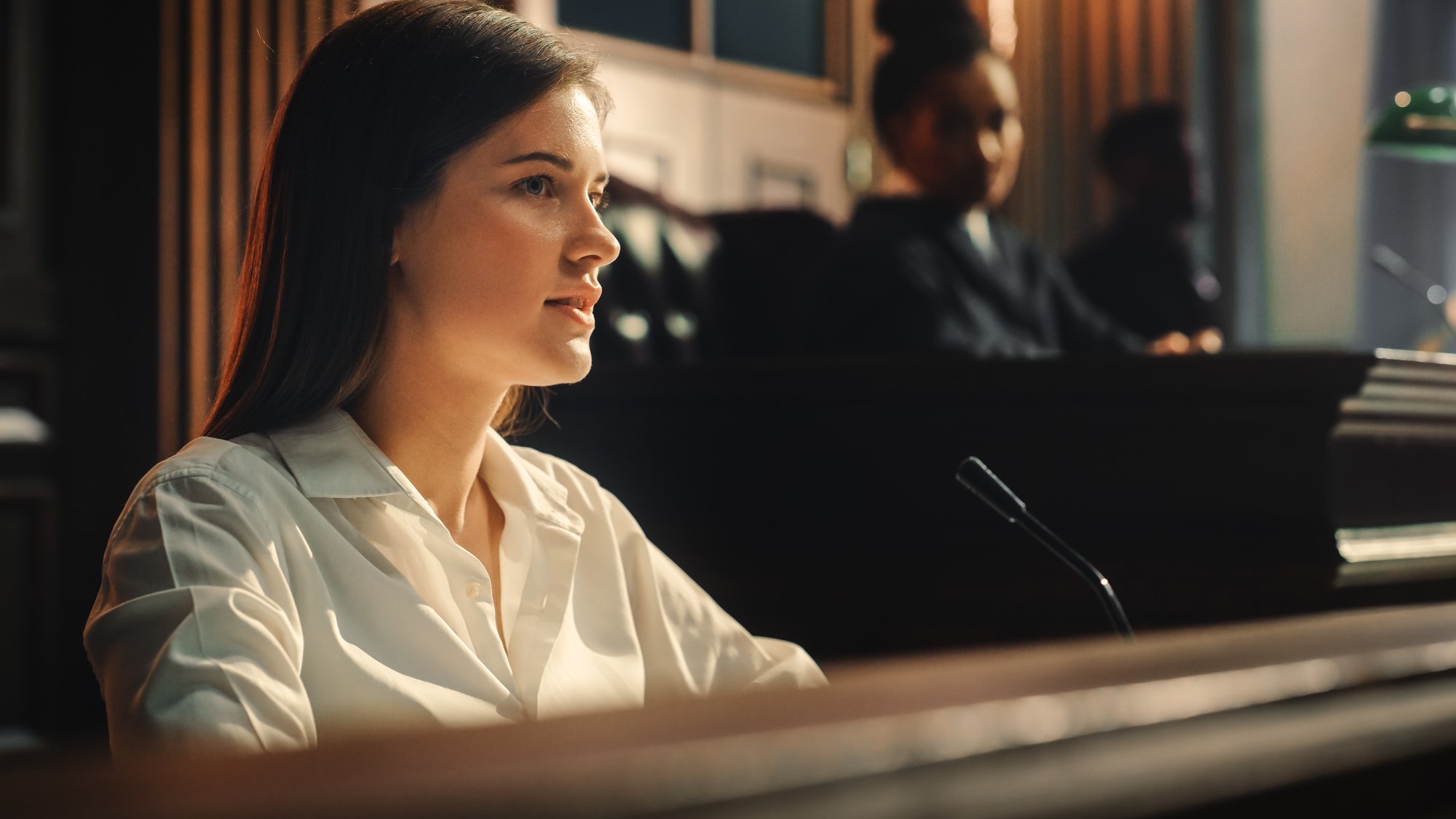 A woman sits at the witness stand.